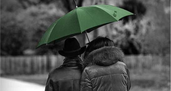 insurance automation: two people huddled under green umbrella